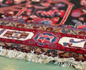 An oriental rug with a vibrant red, blue, and black design, showcasing intricate patterns and cultural influences.