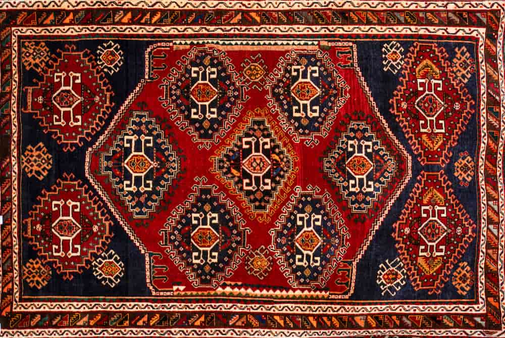 Handwoven Persian rug with red and navy geometric medallions photographed for rug appraisal in North Vancouver.