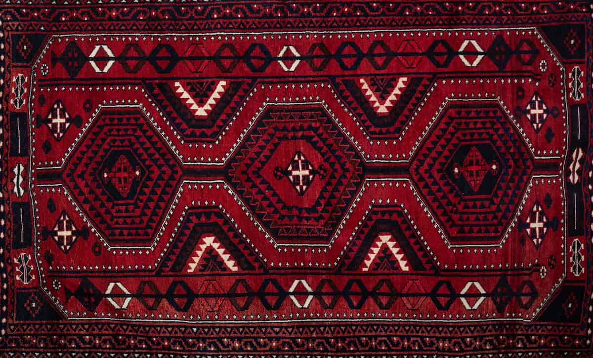 Red Persian carpet with geometric hexagon and tribal motifs available at Shenasi Carpet in North Vancouver